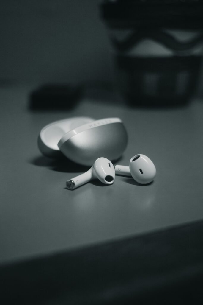 Minimalistic close-up of wireless earbuds with sleek design on a table in monochrome.